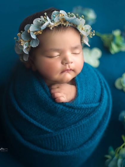 This baby girl is wrapped in a deep teal swaddle, accented with a delicate blue floral crown and matching hydrangeas. The colors are so rich and beautiful.