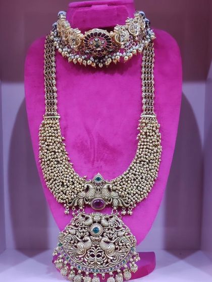 A gorgeous peacock-themed choker and haram set with a large, intricate pendant, perfect for a grand bridal entry.