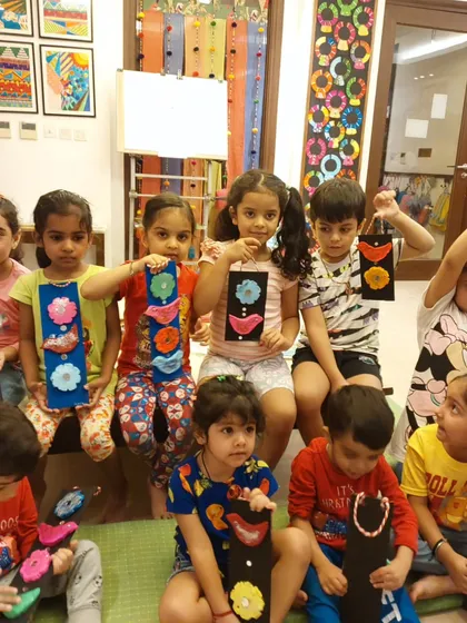 A group of our youngest artists proudly display their finished clay and wood wall hangings. Each piece is a unique expression of their creativity, full of bright colors and fun shapes.