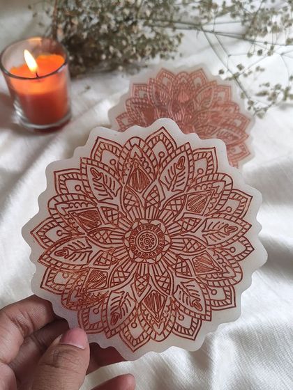 Holding up one of the resin mandala coasters to show the fine lines and beautiful pattern. They are perfect for adding a touch of zen to your coffee break.