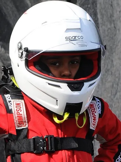 A close-up of a determined young driver in his full safety gear, ready for his first race.