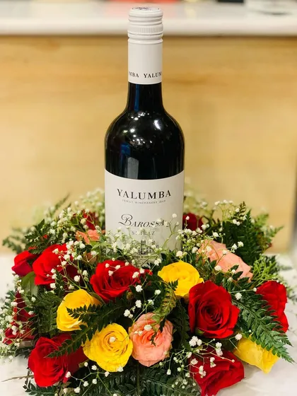 A top-down view of the wine bottle arrangement, highlighting the vibrant colors of the fresh roses against the white tablecloth.
