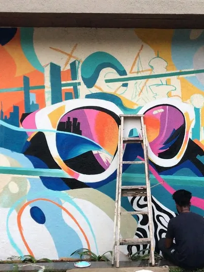 A behind-the-scenes look at the abstract sunglasses mural in progress, showing the scale of the artwork and the painting process.