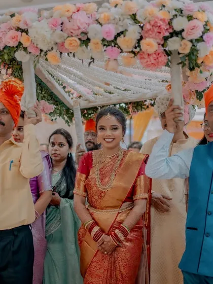 The bride's grand entrance, looking radiant and confident as she walks under the floral canopy.