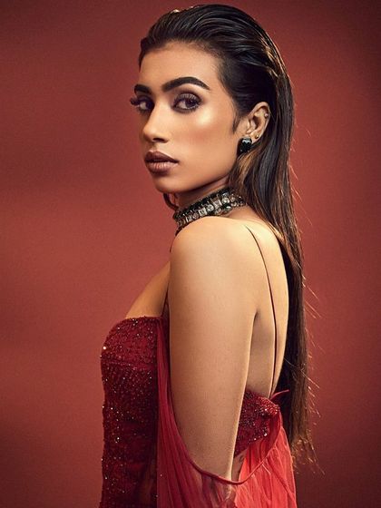 A bold and edgy editorial look. The makeup features a wet-look hair style and a dramatic, smudged lower lash line, creating a high-fashion statement.