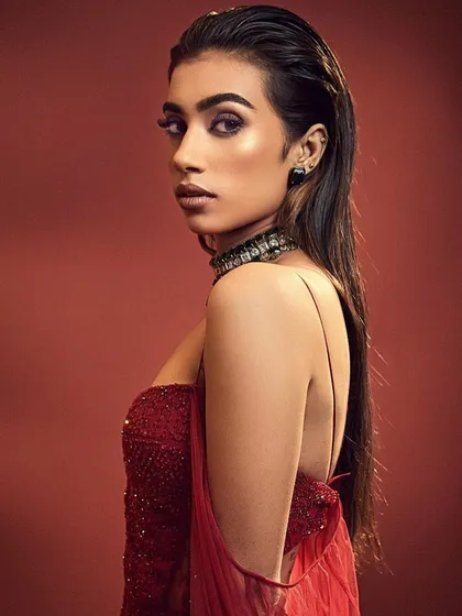 A bold and edgy editorial look. The makeup features a wet-look hair style and a dramatic, smudged lower lash line, creating a high-fashion statement.