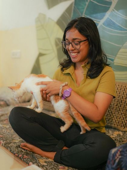 A participant enjoys a playful moment with a ginger and white kitten during our "Paint with Kittens" event in Bangalore.