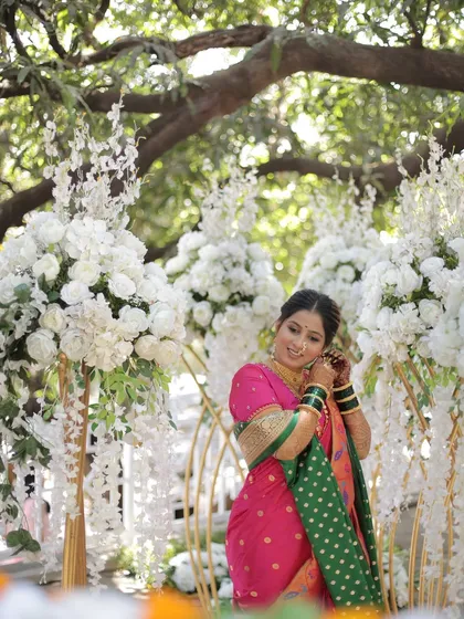 A wide shot of the bride in her beautiful pink Nauvari, standing amidst stunning floral decorations.