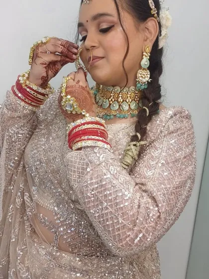 Adjusting the final touches. A candid shot of a bride getting ready in our sequined pastel lehenga and heavy kundan jewellery.