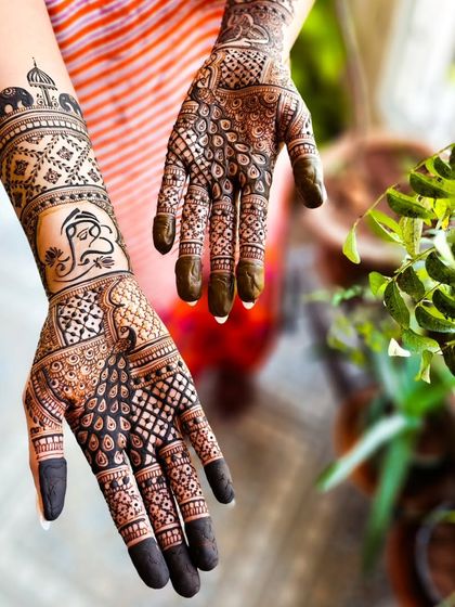 A creative angle showing both the front and back of the hands, featuring a Ganesha on one arm and a peacock on the other.