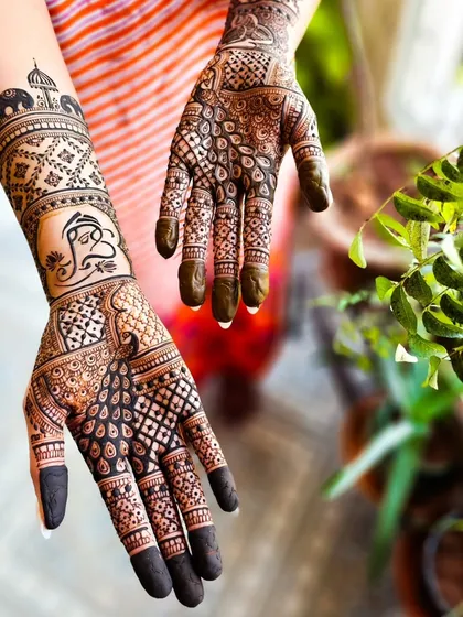 A creative angle showing both the front and back of the hands, featuring a Ganesha on one arm and a peacock on the other.