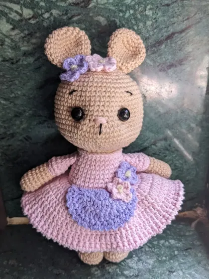 A lovely bunny doll with a purple apron and flowers.