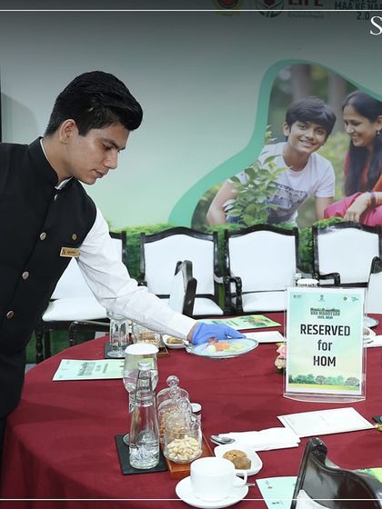 A server carefully placing a dish on a reserved table at the Van Mahotsav event. Our service is always attentive and respectful, especially in the presence of esteemed guests.