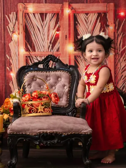 A little girl standing proudly by her vintage chair in a rustic-themed shoot. This pose shows off her new standing skills and her adorable outfit.
