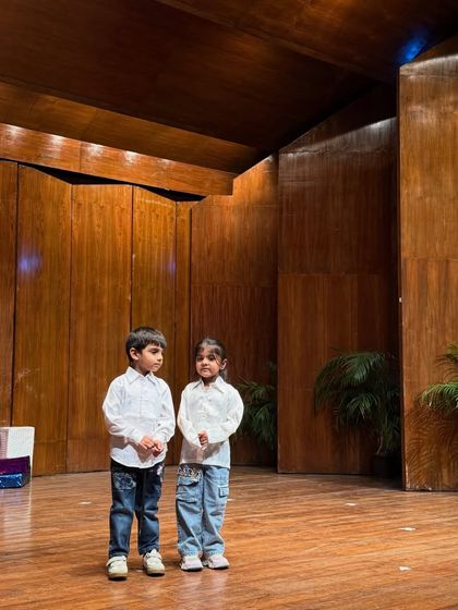 Two of our youngest performers standing confidently on the big stage, ready for their part.