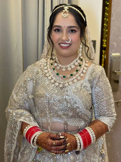 A smiling bride, looking happy and beautiful in her silver lehenga for the night pheras.