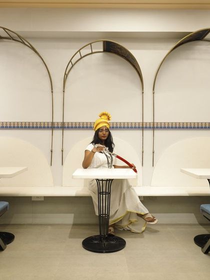 The seating area at Sangam Sweets is framed by delicate, filigree-like metal arches. This design element creates intimate nooks for customers while echoing the traditional architectural themes of the space.