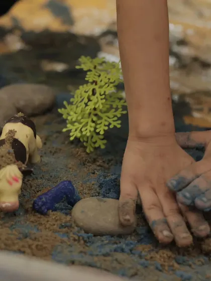 Sensory play is a big part of our early years program. Here, a child explores different textures while creating a story scene.