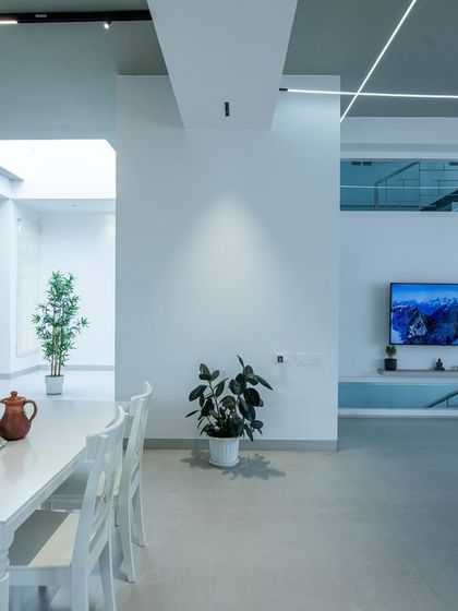 This view shows the dining area within the grey-themed open-plan space. A simple white dining set keeps the look fresh and clean, while a textured stone wall adds a subtle, rustic element.