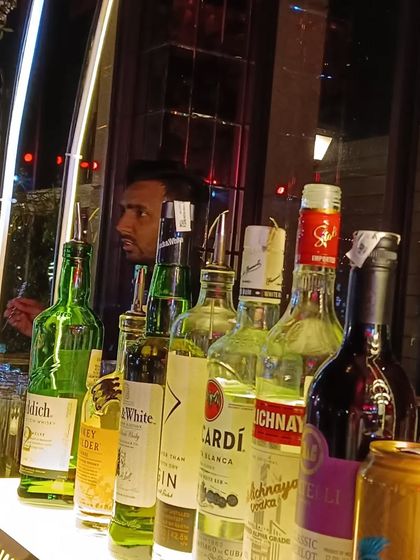 A bartender focused on his craft, seen behind a lineup of premium spirits at an evening event.