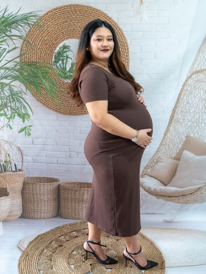 A simple and elegant side-profile shot of a mom-to-be in a brown dress, taken in our boho studio.