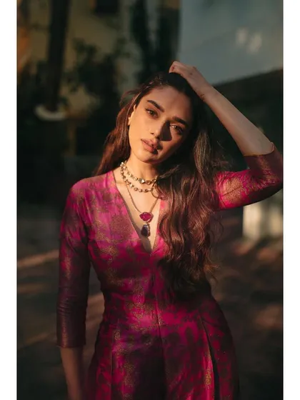 A sun-drenched close-up in the pink brocade jumpsuit, highlighting the beautiful fabric and layered necklaces.