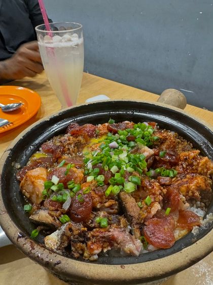 A sizzling claypot filled with rice, chicken, and Chinese sausage, topped with fresh green onions. This traditional cooking method creates a wonderful crispy rice layer at the bottom of the pot, which we call 'fan chiew'.