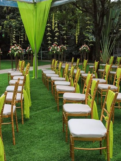 A wide view of a naming ceremony with vibrant green and yellow decor. The open lawn and bright colors create a cheerful and festive atmosphere.