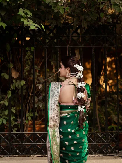 The complete look from the back, showing the fall of the traditional green saree and the beautifully done floral braid.
