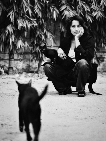 A story in a single frame. A woman watches as one cat walks away, while another stays close. This black and white shot is full of narrative and emotion.