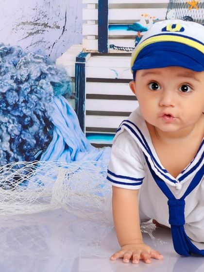 A curious little sailor exploring his ship. The nautical props, like the fishing net and blue wool, create a wonderful sea-faring atmosphere.