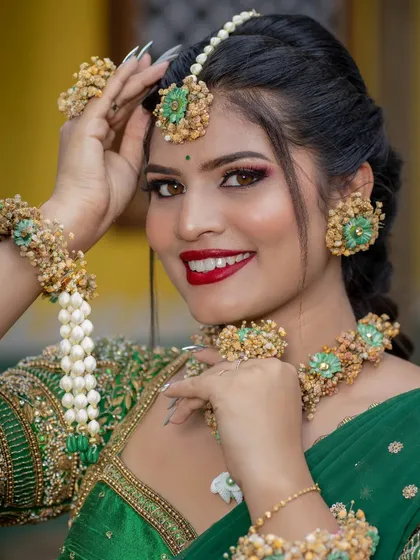 This is a vibrant Haldi or Mehendi look, perfect for pre-wedding celebrations. The makeup features a bright red lip and glowing skin, paired with beautiful floral jewelry to match the festive and joyful occasion.