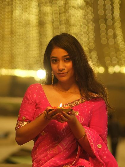 Holding a diya, her face illuminated by its gentle flame. This portrait captures the warmth and devotion of the Dev Deepawali festival in Varanasi.