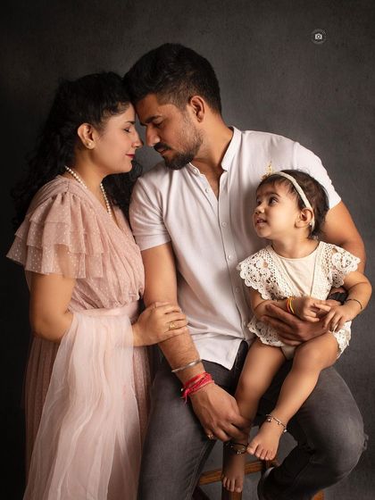 An intimate family portrait capturing a quiet moment of connection between the parents, with their daughter looking on.