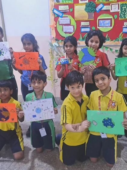 A group of students from the primary wing proudly holds up their Earth Day posters. Their artwork reflects their understanding of environmental themes and their desire for a greener planet.