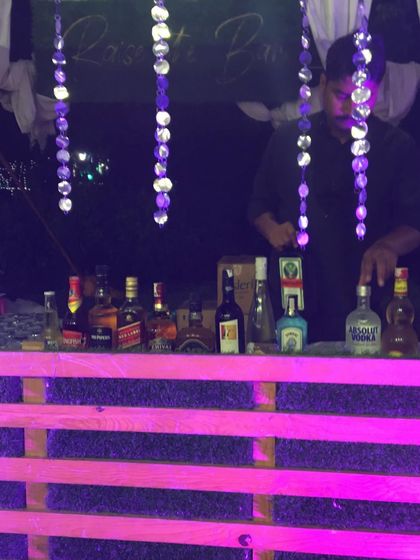 A bartender at our rustic pink bar, preparing drinks with a full selection of spirits.