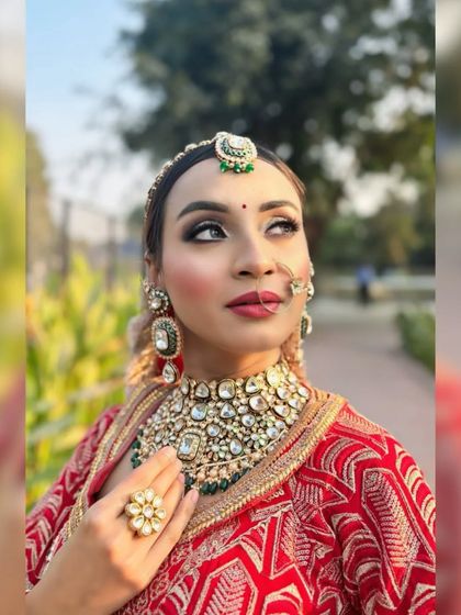 A close-up of the bride, looking up. This angle highlights the eye makeup and the maang tikka.
