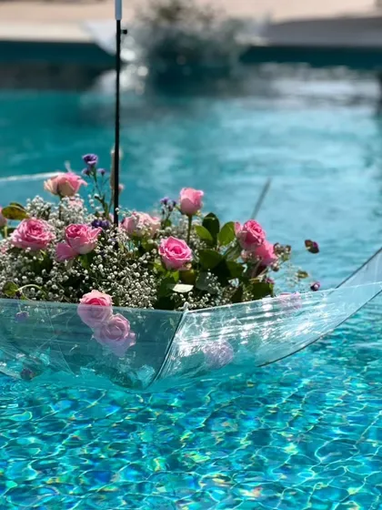 A whimsical and creative decor detail: a clear umbrella filled with pink roses, floating gracefully in the swimming pool.