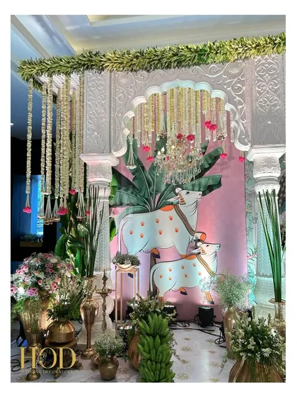 A stunning stage corner inspired by Pichwai art, featuring painted Nandi figures, banana leaf backdrops, and traditional floral arrangements.