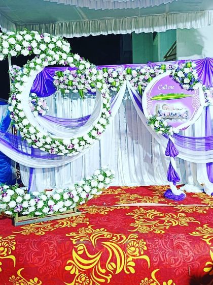 A unique double-moon cradle setup for a naming ceremony. The decor uses white and purple flowers with matching drapes for a coordinated and grand look.