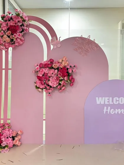 An elegant 'Welcome Home' backdrop for a baby girl. This setup uses modern pink arched panels decorated with beautiful bouquets of pink flowers.