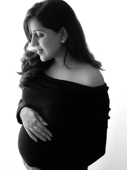 A quiet, contemplative black and white portrait of a mother-to-be. She looks down at her bump with so much love, a moment of pure connection.