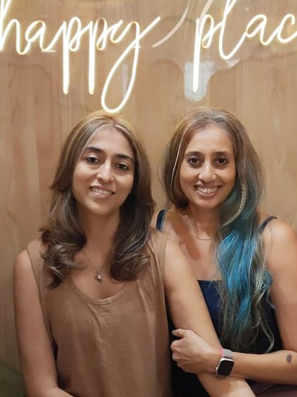 Two friends showing off their new hairstyles. One has a chic, natural look, while the other sports a fun pop of blue.