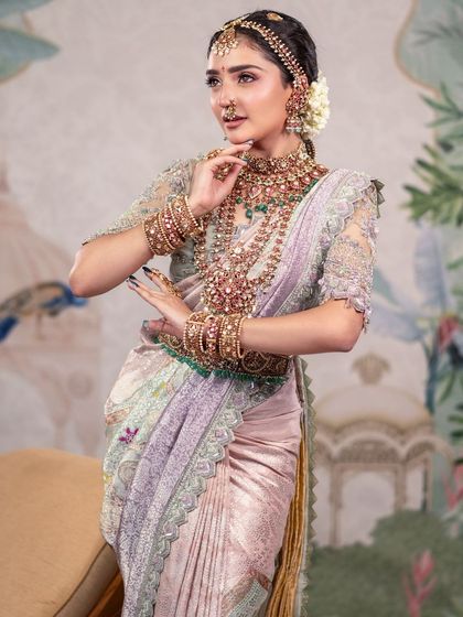 A graceful and dynamic pose, showcasing the beautiful drape of the saree and the model's elegant posture. The hand-painted backdrop adds a touch of classic art to the composition.