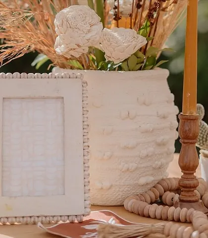 More details from the 'Boho vibes' setup, including a beaded photo frame, textured candles, and small cacti, all contributing to a handcrafted, natural feel.