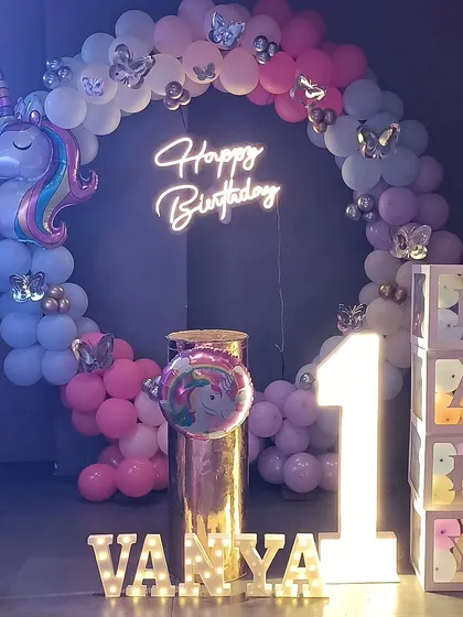 A closer look at the unicorn party backdrop, focusing on the neon sign, marquee letters, and "BABY" blocks.