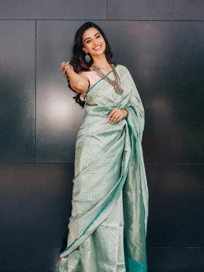 A full-length shot of the teal silk saree against a dark background, making the color pop. The styling is poised and elegant, showcasing a complete, head-to-toe look.
