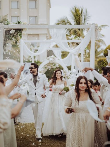 The grand entrance to the reception. The couple walks through a shower of confetti, surrounded by their cheering friends and family, a moment of pure joy and celebration.
