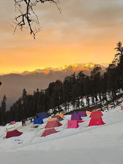 A stunning sunset view over the snow covered campsite during our Kedarkantha trek. Camping in the Himalayas offers some of the most beautiful and serene moments you can imagine.