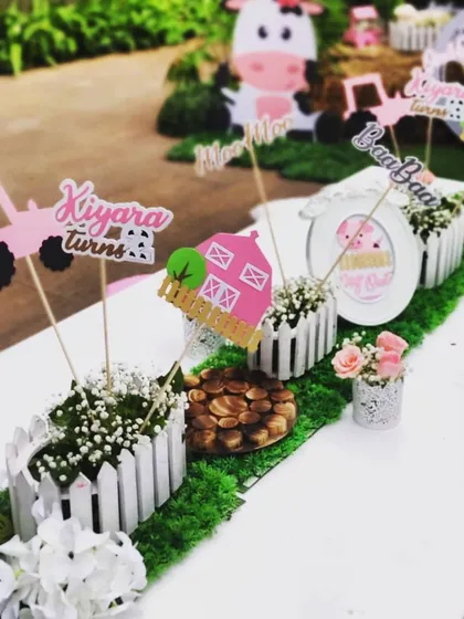 A closer view of the adorable, handcrafted centerpieces on the children's dining table. These little details, from the picket fences to the custom signs, help create a cohesive and immersive farm party experience.
